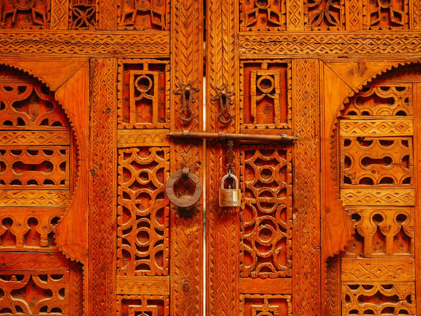 Traditional granary doors carved into weathered wood against the cliff face in Songo
