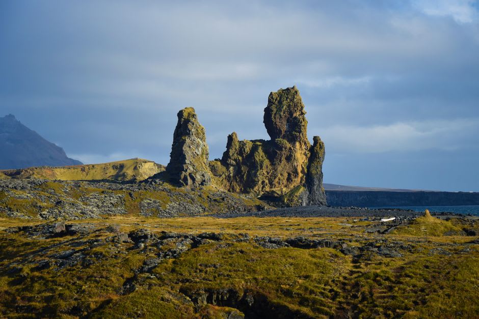 Red and grey volcanic cliff formations at Point Baptiste near Calibishie with waves breaking below