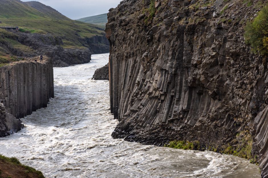 Narrow black volcanic rock walls of Titou Gorge rising steeply on either side of a channel of dark water