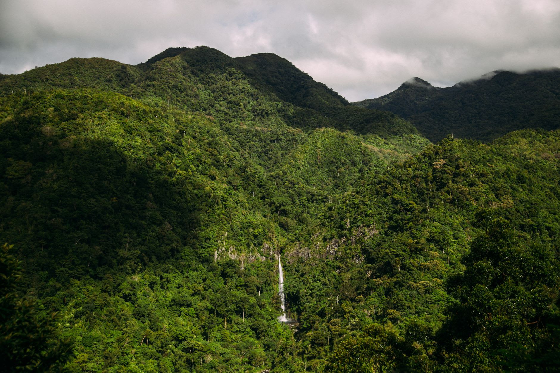 Looking up at both falls from the boulder field below — the Father fall white and thin, the Mother fall broader and pale green-tinged