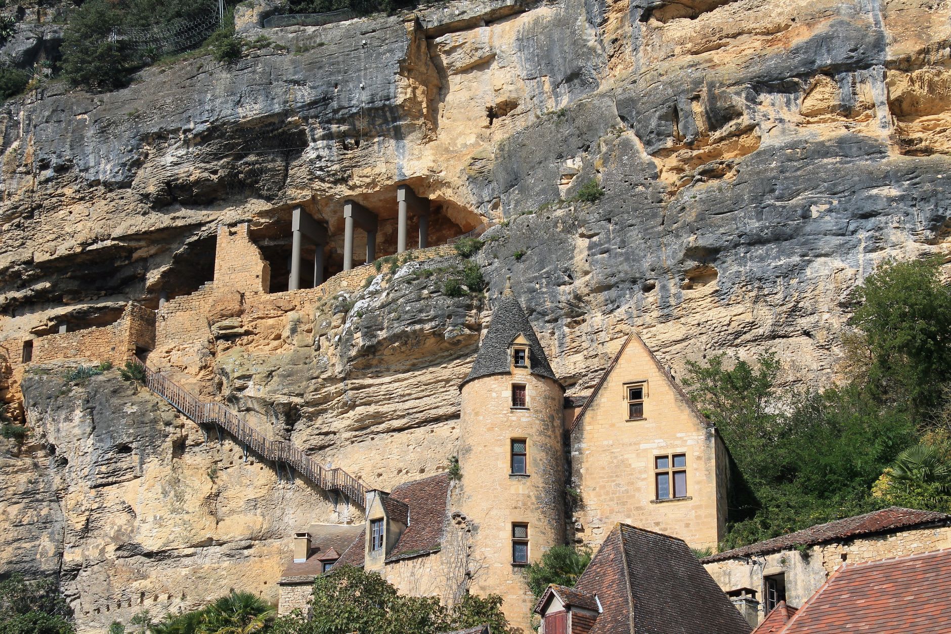 Terraced gardens of Château de Marqueyssac overlooking the Dordogne river valley at dusk, with La Roque-Gageac visible below