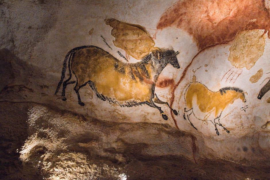 Close-up of ochre and black pigment horses painted along the curved cave wall