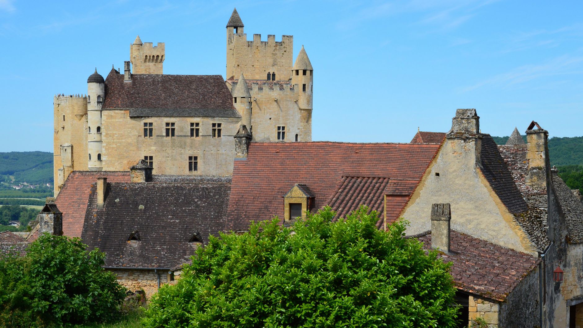 A stall at Sarlat's Saturday market piled with duck confit, foie gras, and Périgord truffles under golden autumn light
