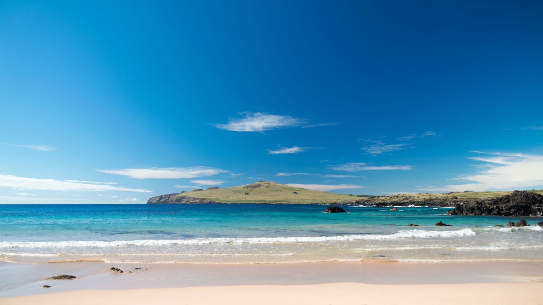 Swimmers in the turquoise water at Anakena Beach with Ahu Nau Nau's moai visible on the shore behind them