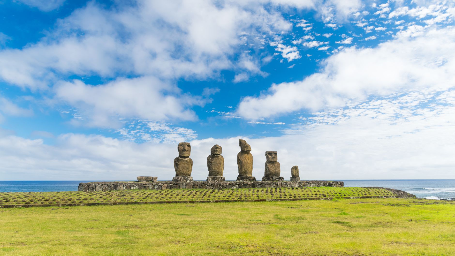 The spherical stone of Te Pito Kura surrounded by smaller stones on its platform, the Pacific visible in the background