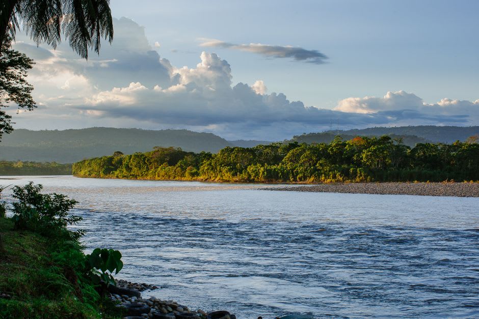 The waterfront of Coca at dusk with the Napo River glowing orange under the setting sun
