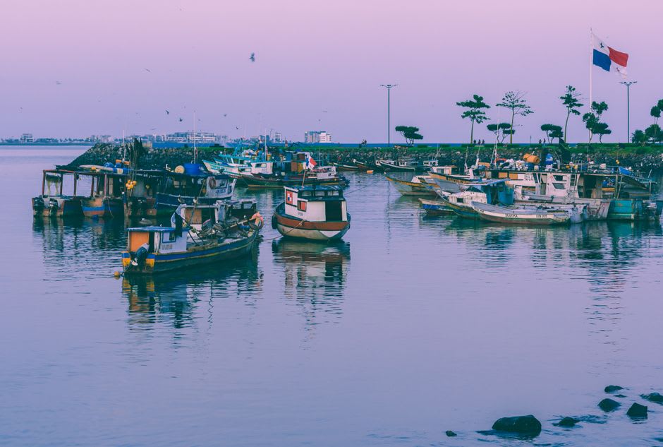 Small fishing boats moored in the harbor at La Libertad with the pier stretching into the Pacific behind them