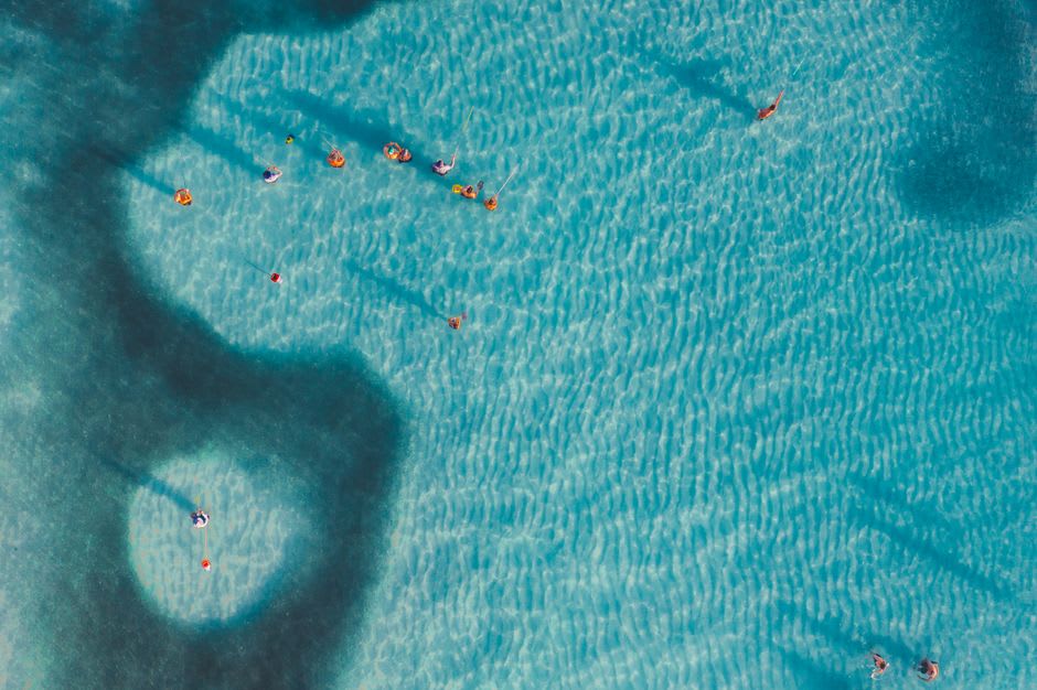 Swimmers floating in the turquoise waters of Laguna de Alegría with the crater walls rising around them