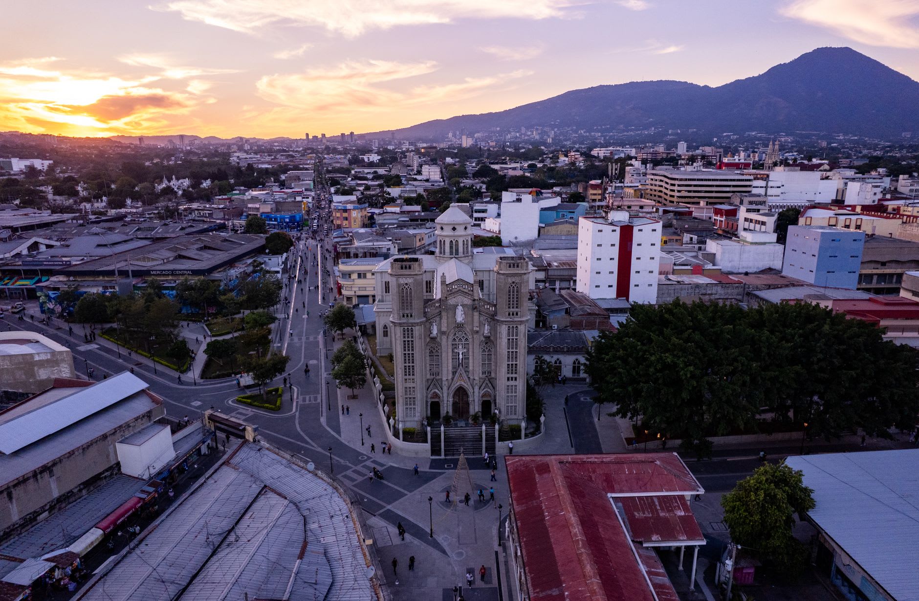 The colonial church of Nahuizalco at night with lanterns glowing along the street in front and market stalls lit by candlelight