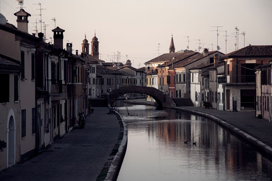 A canal-side street in Comacchio's historic center lined with pastel houses