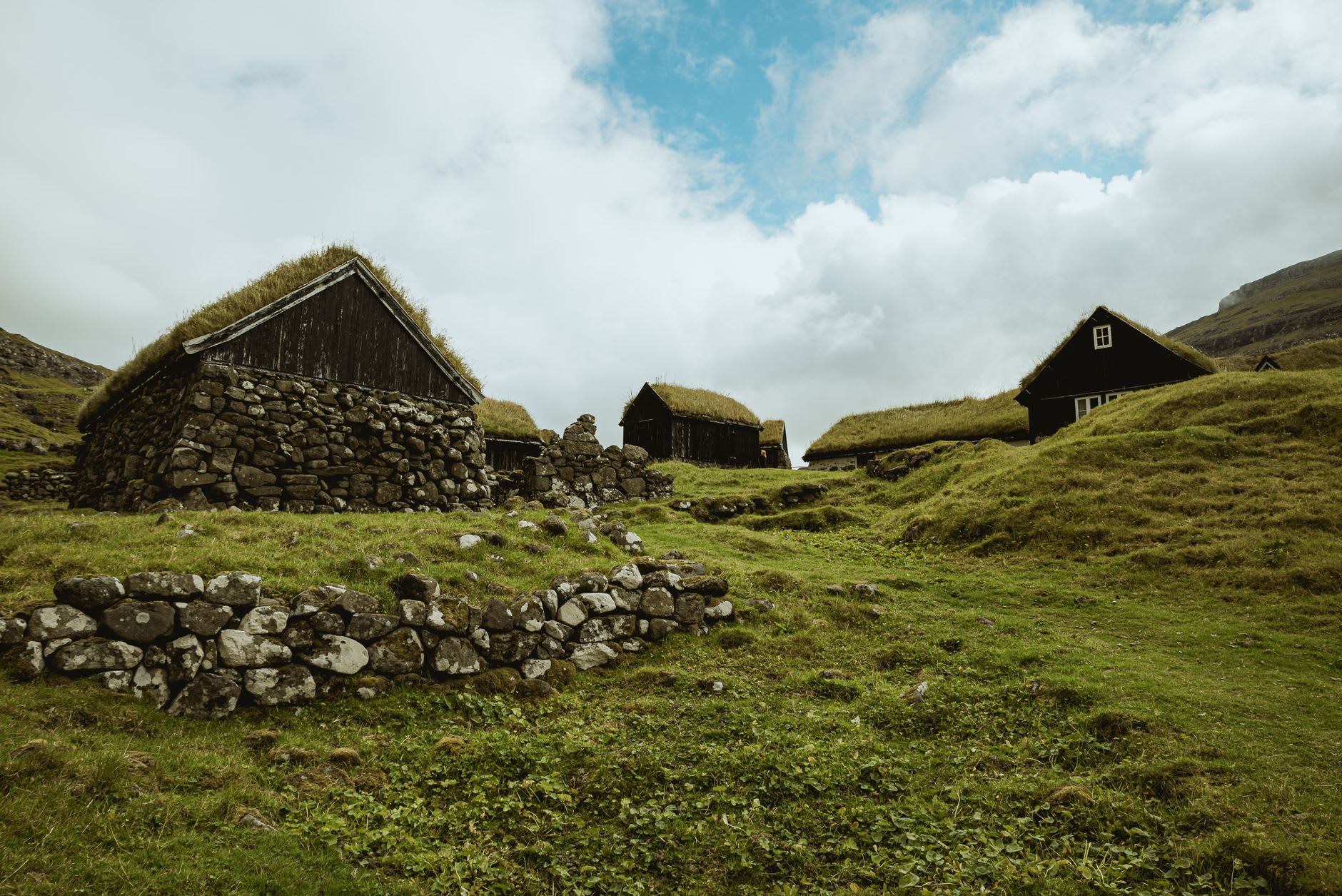 La antigua granja Roykstovan en Kirkjubøur con las ruinas de la catedral visibles al fondo frente al sonido