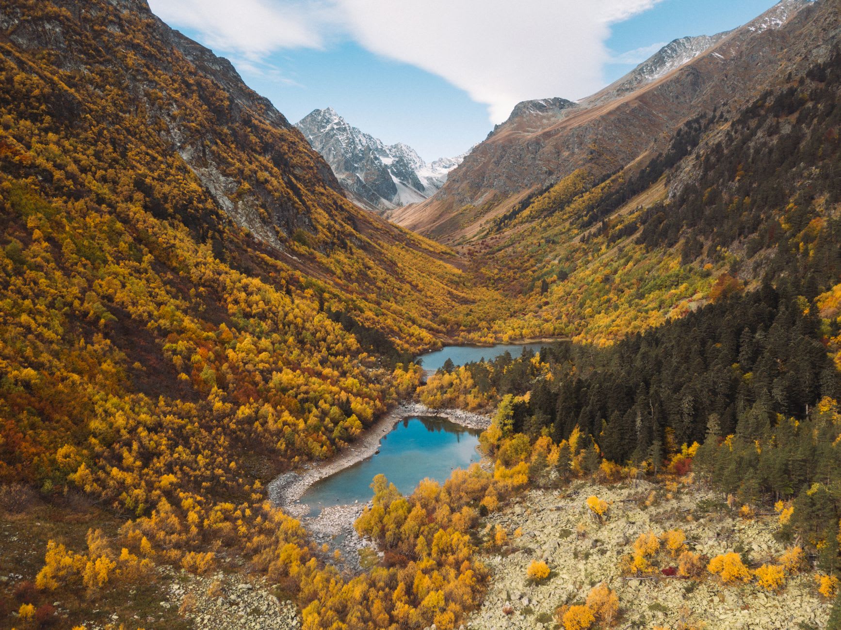 The river gorge at Shakhimardan with fast-running glacier-green water between boulder fields and pine trees