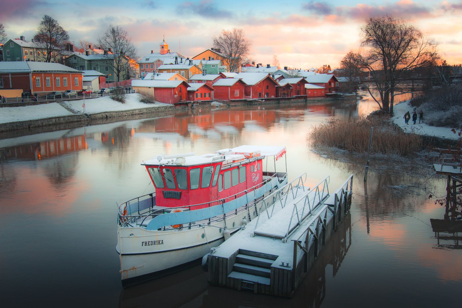 The red wooden warehouses of Porvoo's Old Town reflected in the still surface of the Porvoonjoki river on a calm September morning