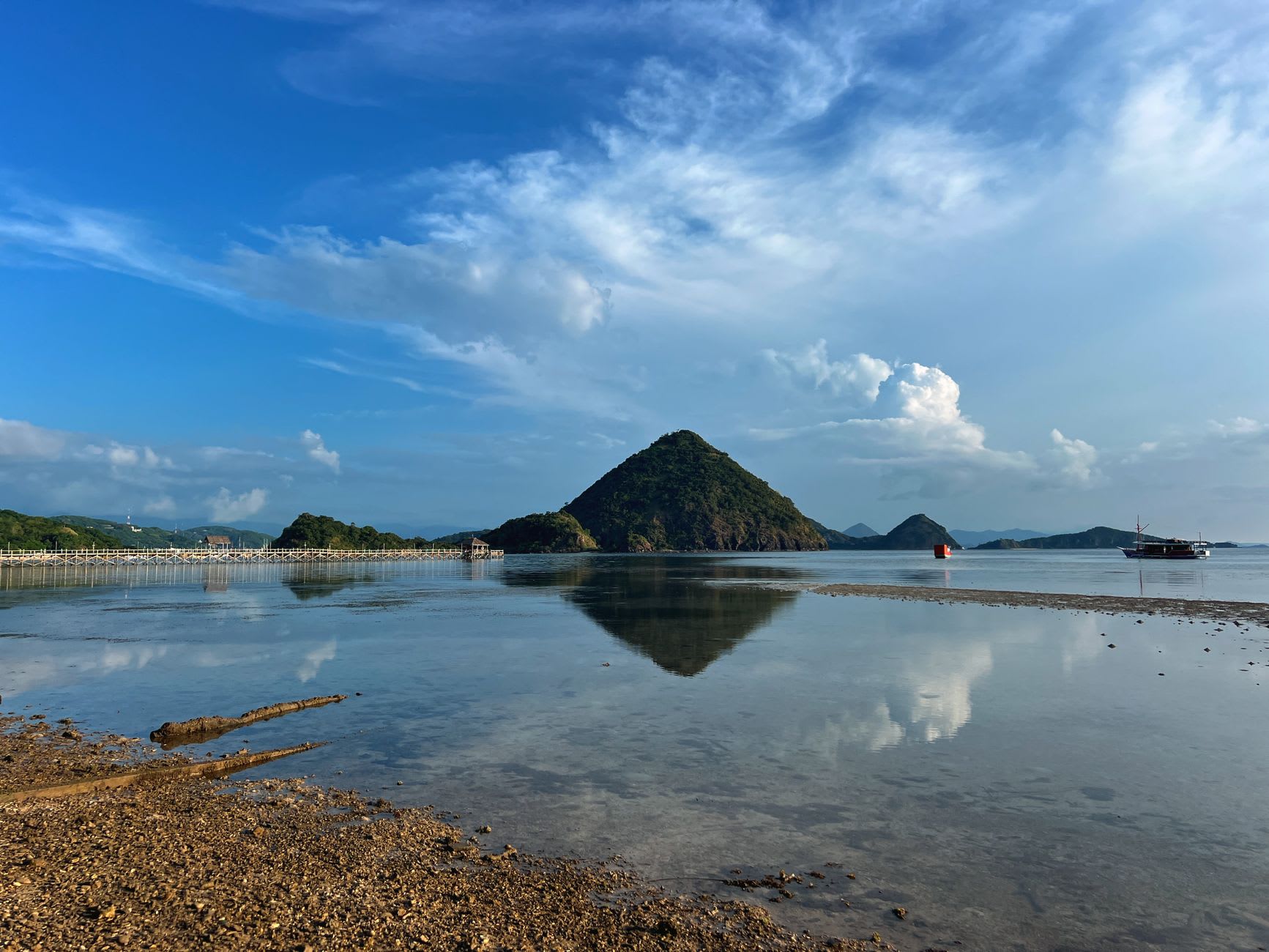 Fishing boats and outriggers moored in the shallows of Maumere Bay with a small island and the central Flores ridge in the distance