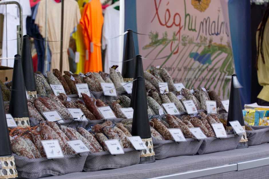 Stalls piled with Corsican charcuterie, cheese, and chestnut products at the Place Foch morning market in Ajaccio