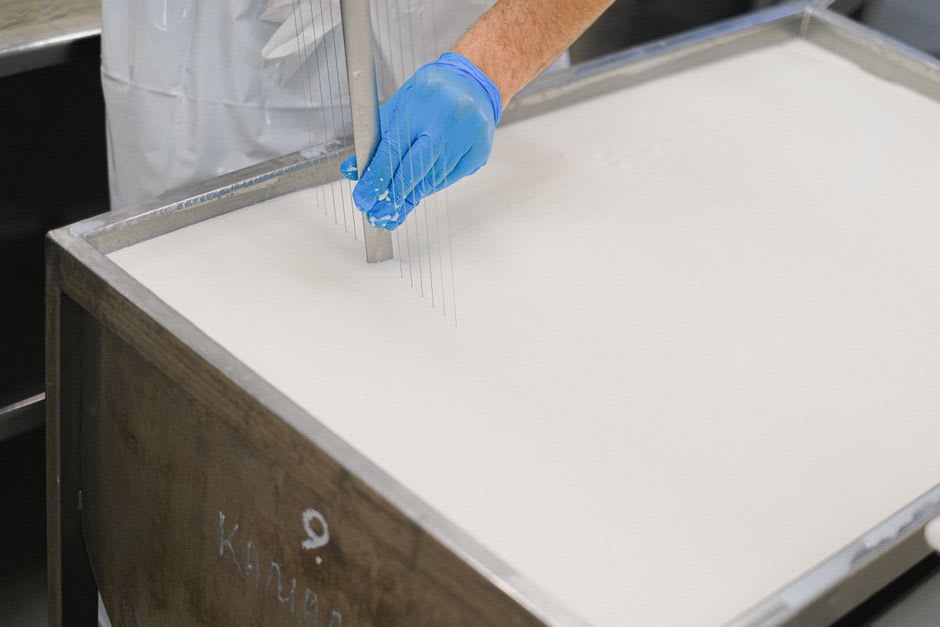 A worker at the Moulin Richard-de-Bas lifting a wire frame of hand-pressed paper from a vat inside the old mill