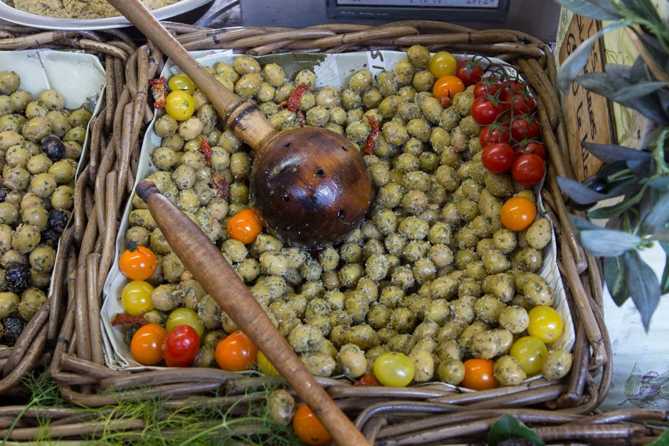 Colourful market stalls of olives, tapenade, and produce under the iron-roofed Marché Provençal in Antibes