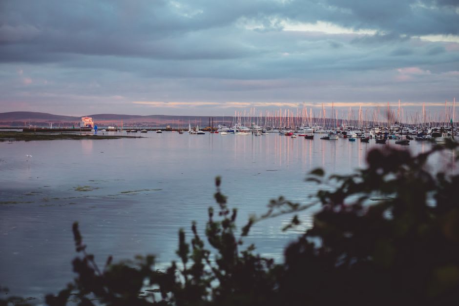Sailboats and small craft moored in the tidal channel below Auray with the Gulf of Morbihan beyond