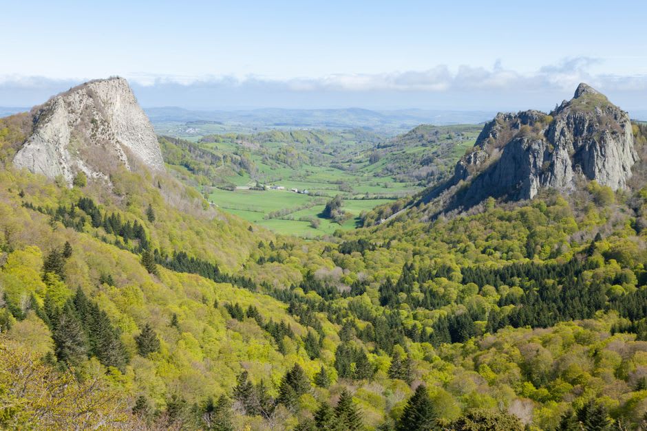 Green volcanic hills of the Cantal massif rising behind farmland just outside Aurillac