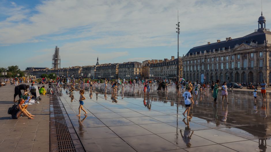 Locals sitting on the stone edge of the Bassin des Ladres public hot spring pool in the centre of Ax-les-Thermes