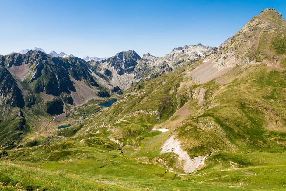 View from the ridge above Ax-les-Thermes across green Pyrenean valleys toward distant peaks