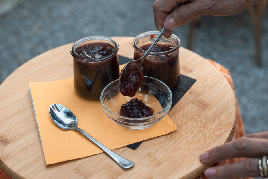 A jar of hand-seeded redcurrant jelly beside a goose quill on a wooden table in Bar-le-Duc