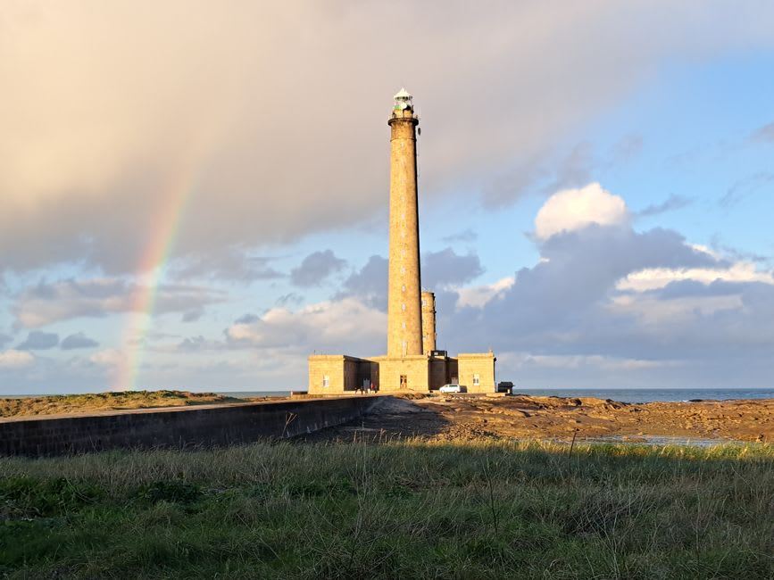 The black-and-white striped granite tower of the Phare de Gatteville lighthouse against a grey Channel sky