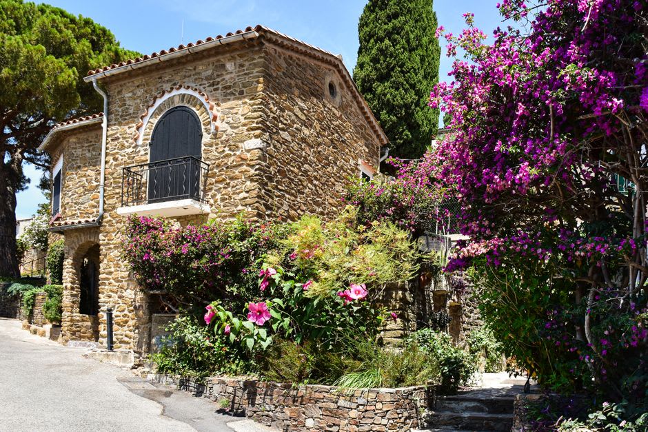 A narrow stone stairway in Bormes-les-Mimosas lined with pink bougainvillea climbing the old village walls