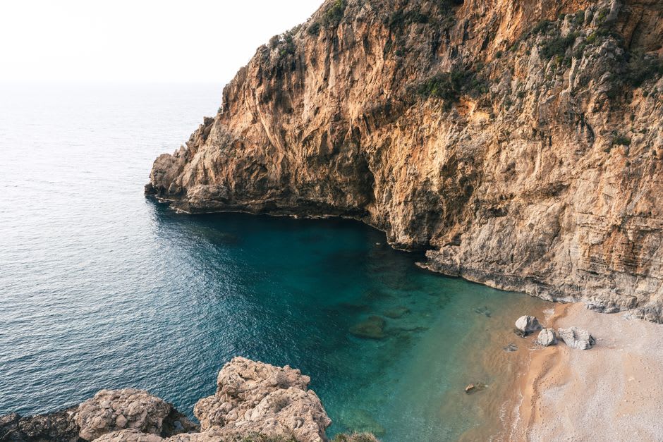 A quiet cove near Cargèse with clear turquoise water below maquis-covered cliffs in late afternoon light