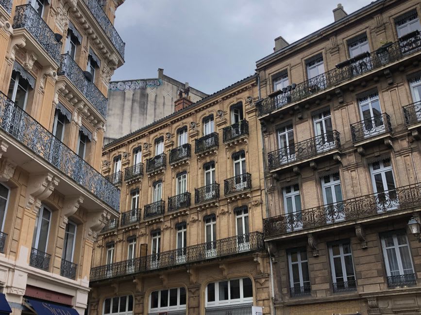 The ornate Belle Époque facade of a thermal bathhouse in Cauterets with wrought-iron balconies above the street