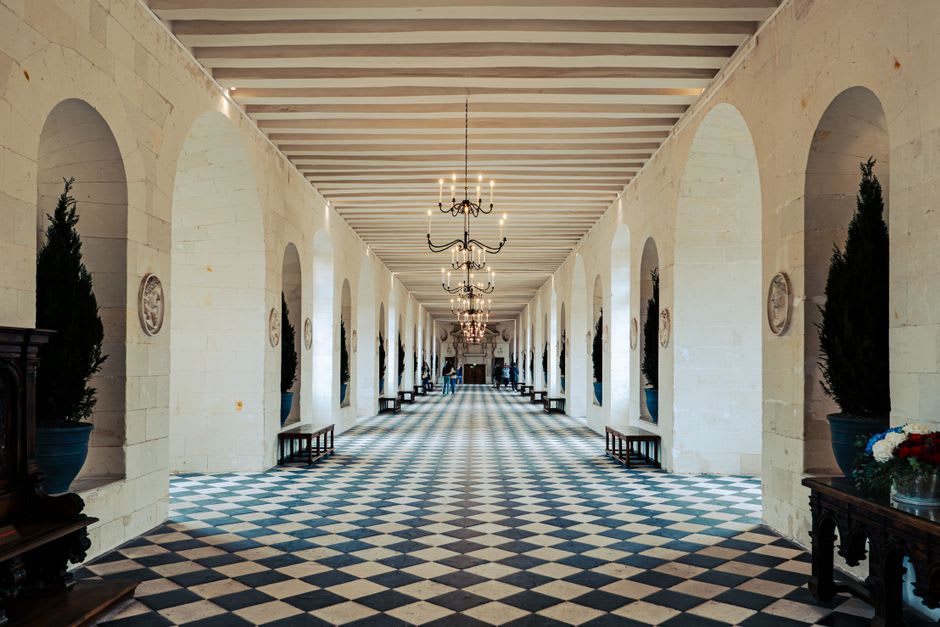 The checkerboard-floored Grande Galerie of Chenonceau stretching across the river with light pouring through tall windows