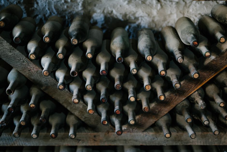 Rows of aging wine bottles in a limestone cave cellar cut into the cliff below Chinon's fortress