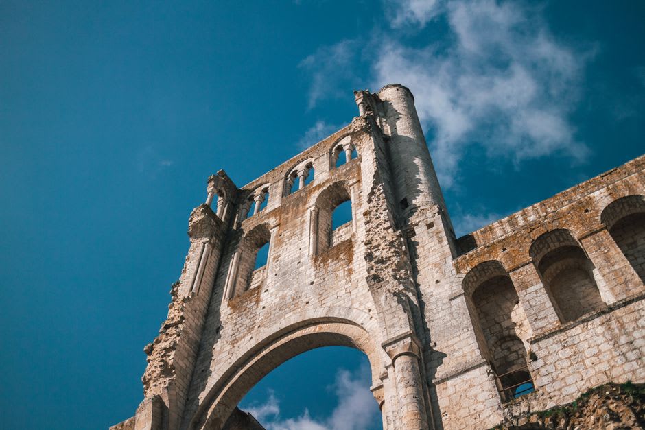 The Romanesque bell tower and surviving arches of the ruined Abbey of Cluny against a Burgundy sky