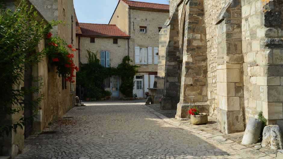 A quiet medieval stone street in Cluny lined with Romanesque houses near the site of the former abbey