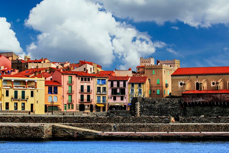 A reproduction Fauvist painting on a stand along Collioure's waterfront, matched against the real harbour view behind it