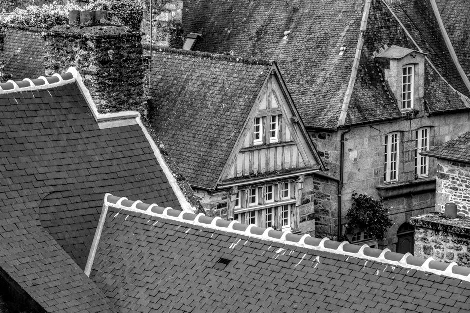 The ramparts of Dinan with slate rooftops and the spire of the Basilique Saint-Sauveur against the sky