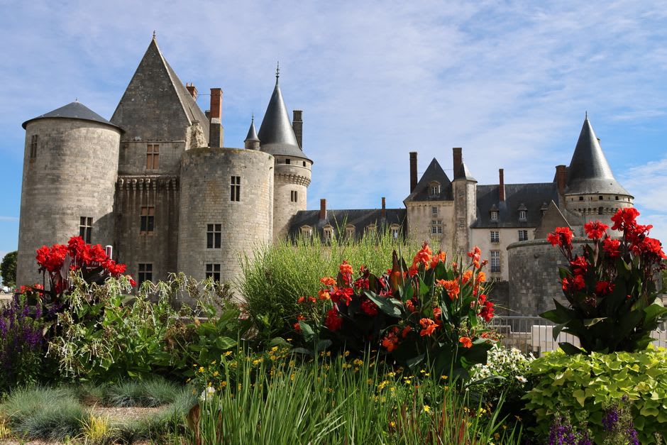 The four corner towers of Château de Duras seen from the terraced gardens below, with the Dropt valley stretching out behind