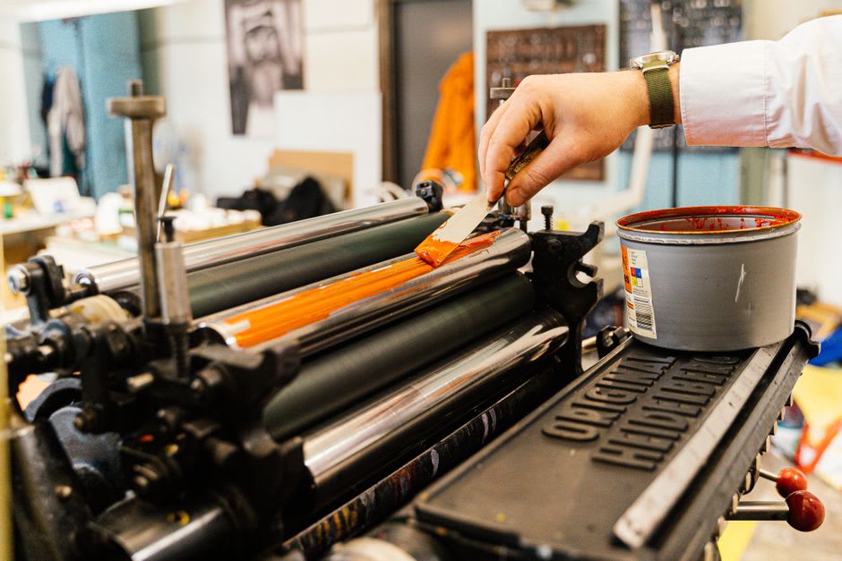 A vintage hand-cranked printing press at the Imagerie d'Épinal with a freshly inked woodblock print