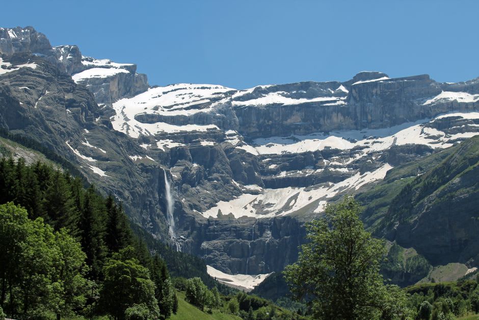 Hikers walking the path toward the base of the Cirque de Gavarnie with the Grande Cascade visible in the distance