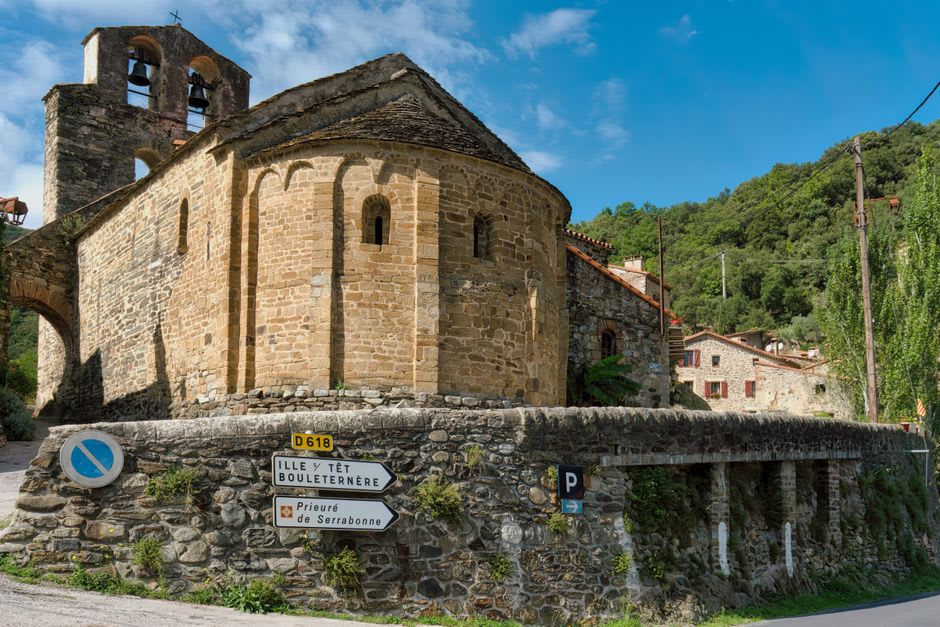 The small stone Romanesque church of Gavarnie village with the high Pyrenees rising directly behind it
