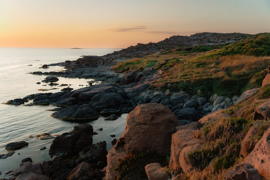 The reddish porphyry islets connected by a causeway to L'Île-Rousse, glowing deep pink-orange at sunset
