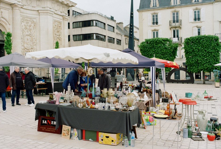 Antique furniture and vintage brocante items laid out along the riverside stalls of the Sunday market in L'Isle-sur-la-Sorgue