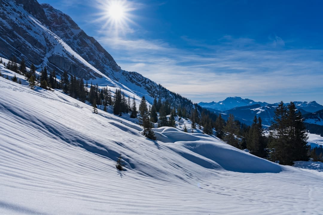 Skiers on a wide snow-covered piste in La Clusaz with the jagged limestone peaks of the Aravis massif rising behind