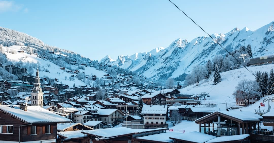 Snow falling at dusk over La Clusaz's village church and traditional wooden chalets with warm lit windows