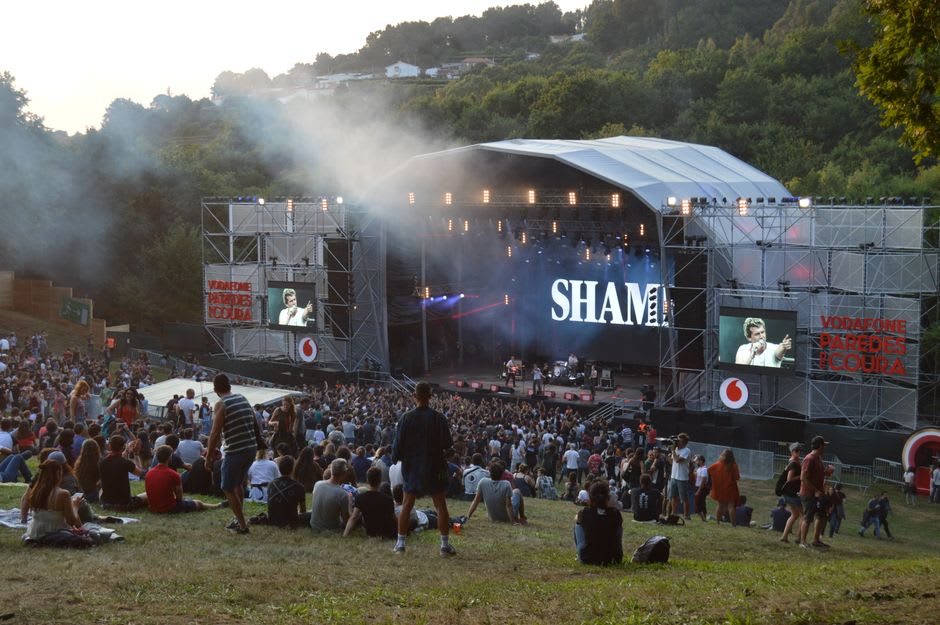 Rows of festival-goers seated under towering plane trees for an open-air piano concert at the Château de Florans
