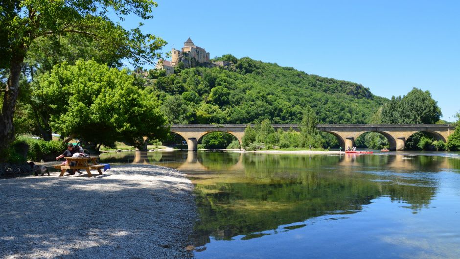 The Dordogne river at Lalinde in evening light, with the old bastide town's rooftops visible along the bank