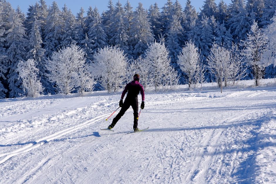 Cross-country skiers gliding along a groomed trail beside the frozen, snow-ringed Lac des Rousses