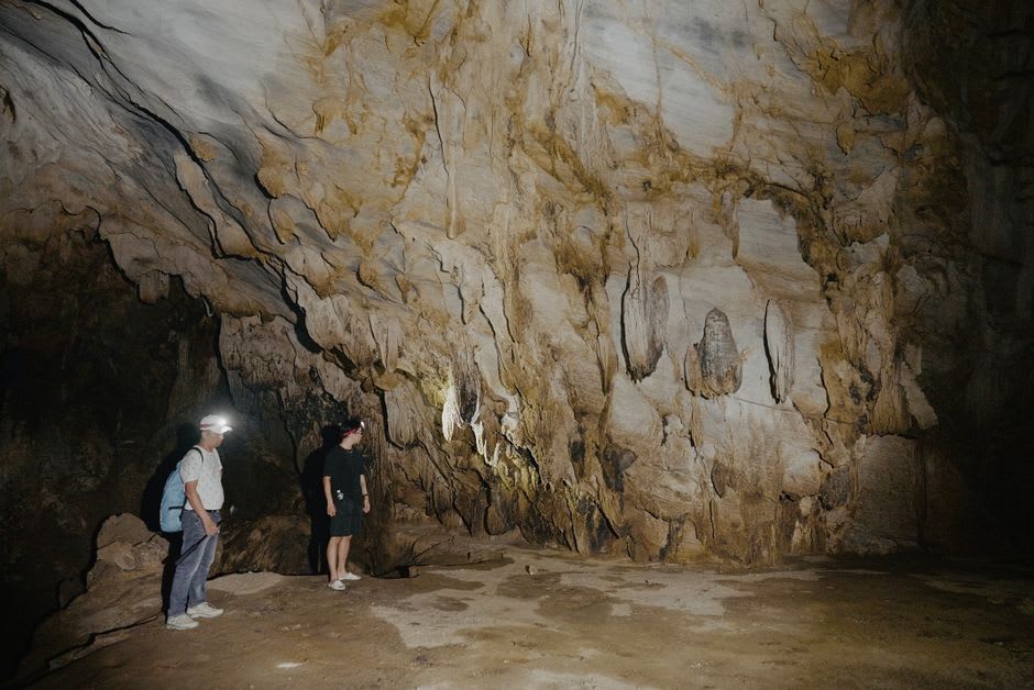 Pilgrims touching the worn rock wall of the grotto where Bernadette reported her visions