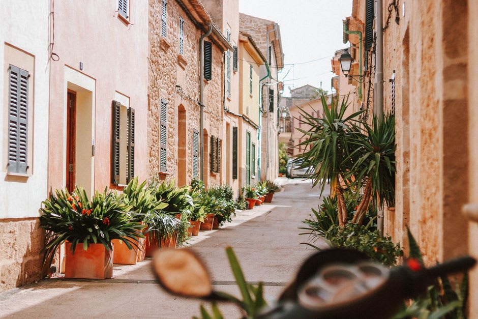 A narrow shuttered street in the old town of Manosque with stone façades in warm ochre tones