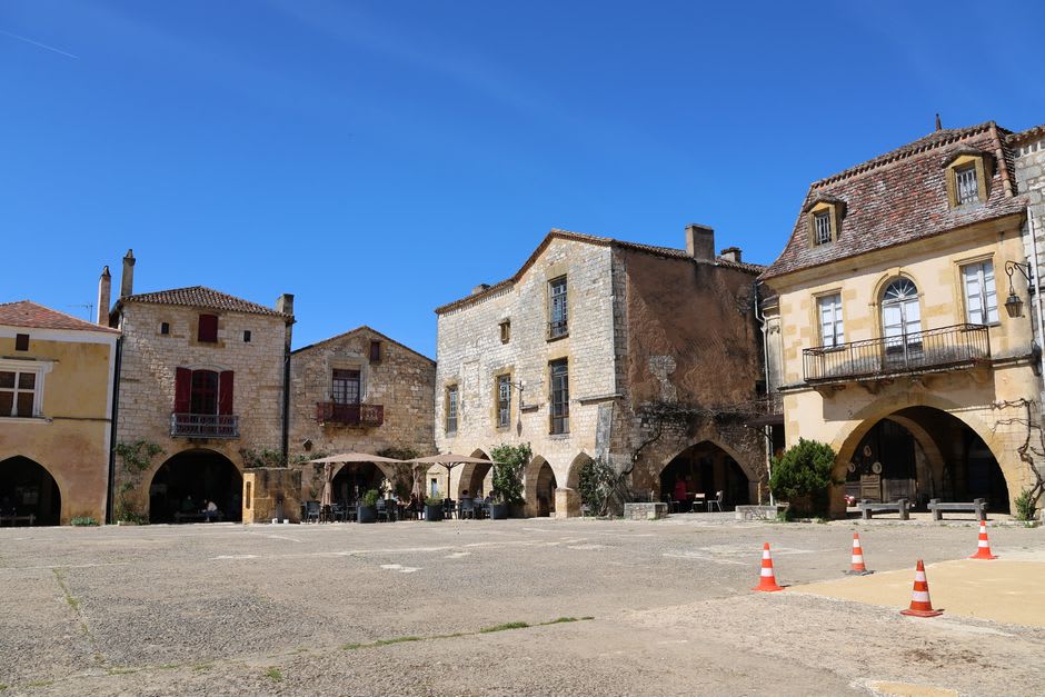 The stone arcades surrounding Monpazier's central Place des Cornières with the timber-roofed market hall in the center